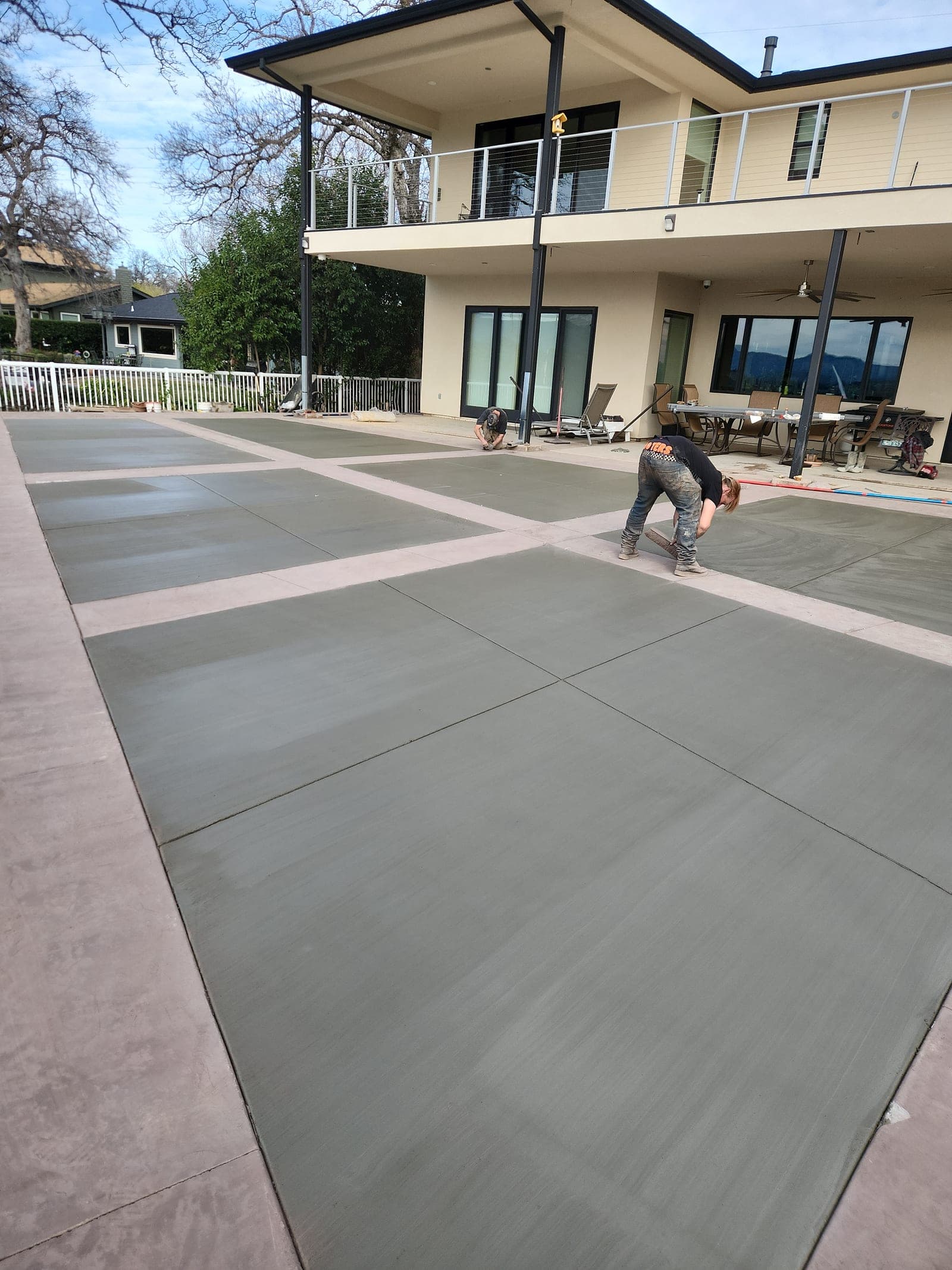 Two of the crew hand-troweling the panel field beside the house