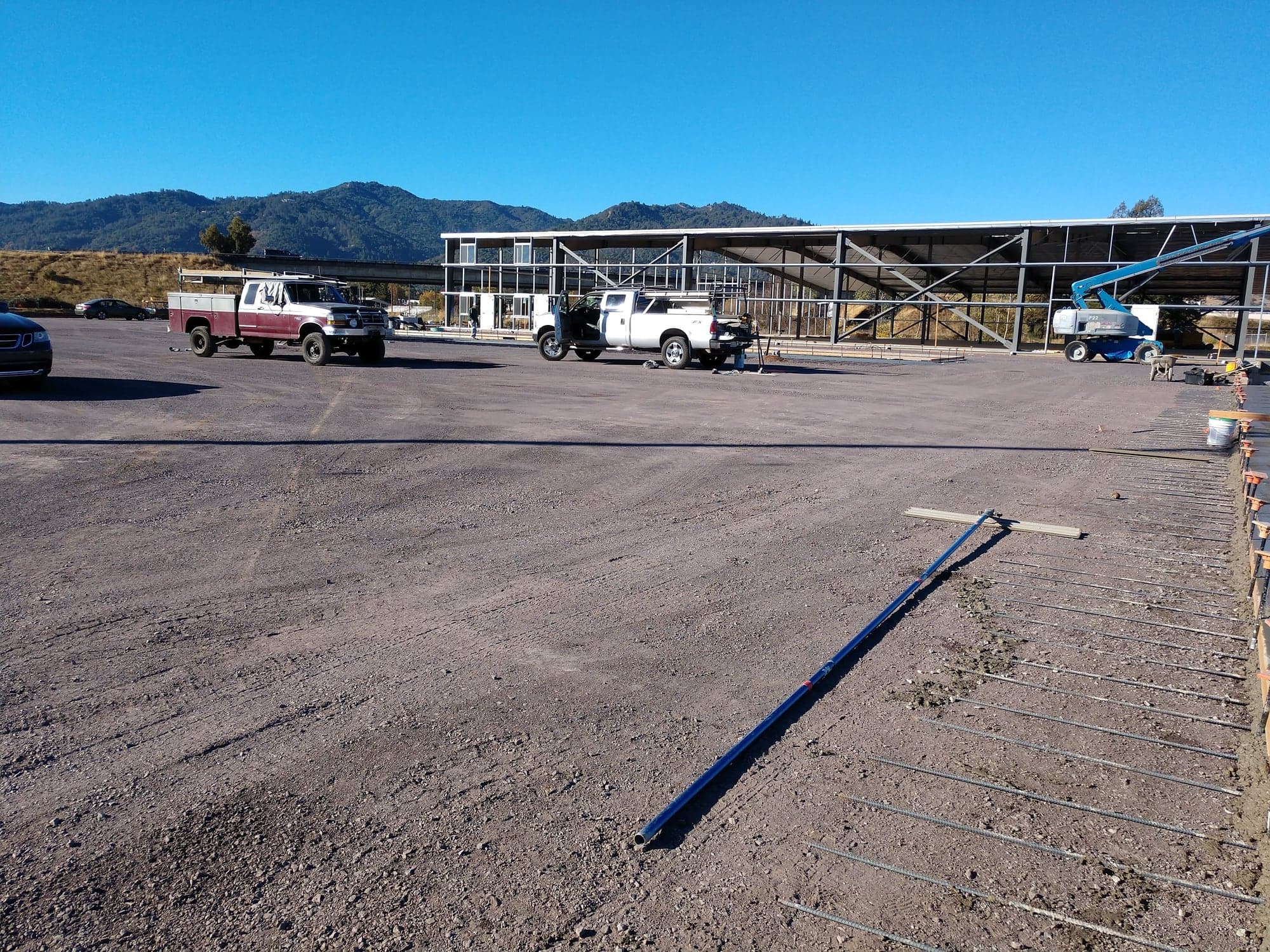 A large commercial building pad prepared and reinforced in front of a steel-framed building under construction