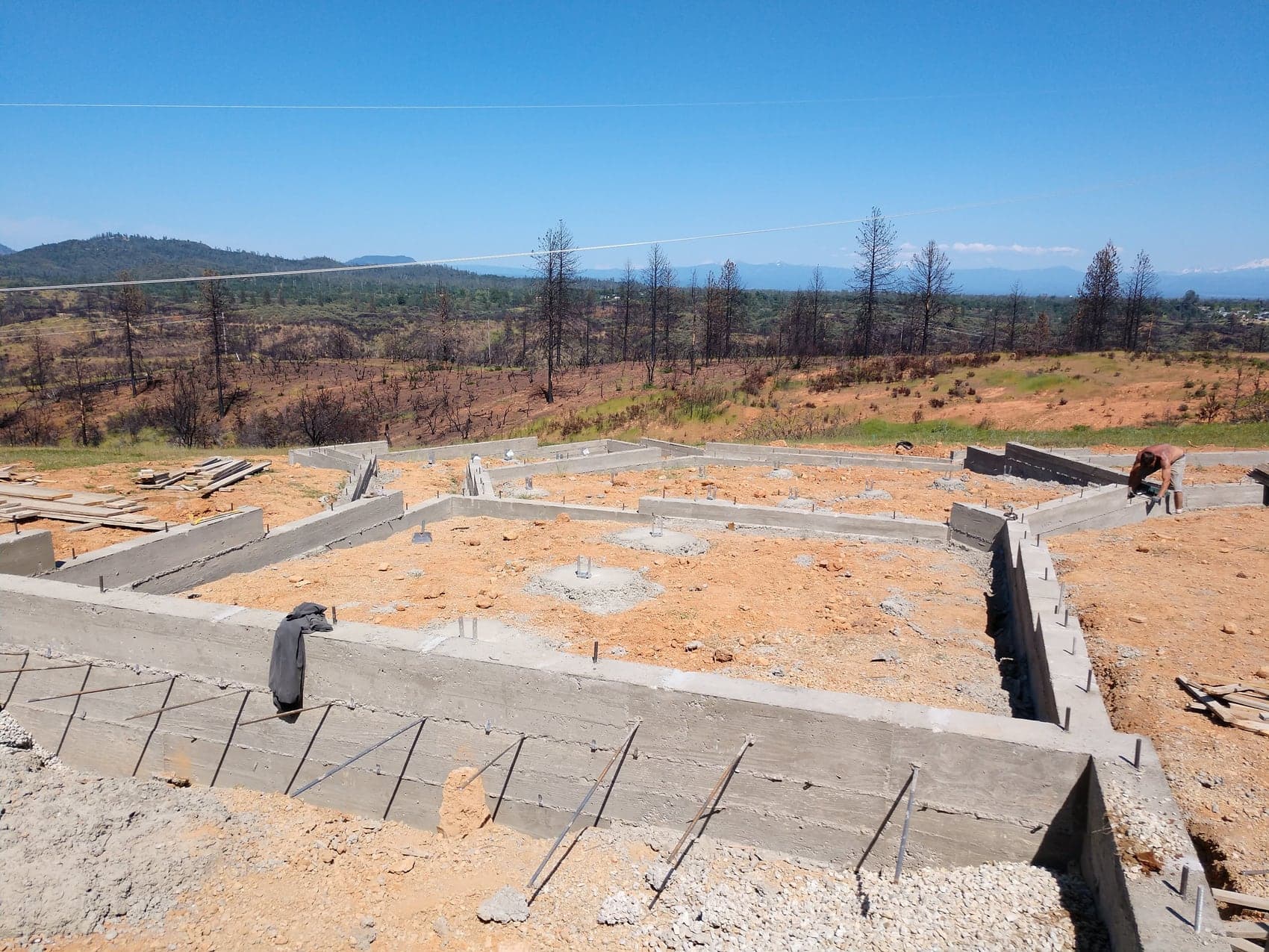 The stripped foundation showing square stem walls, interior pads and anchor bolts ready for framing