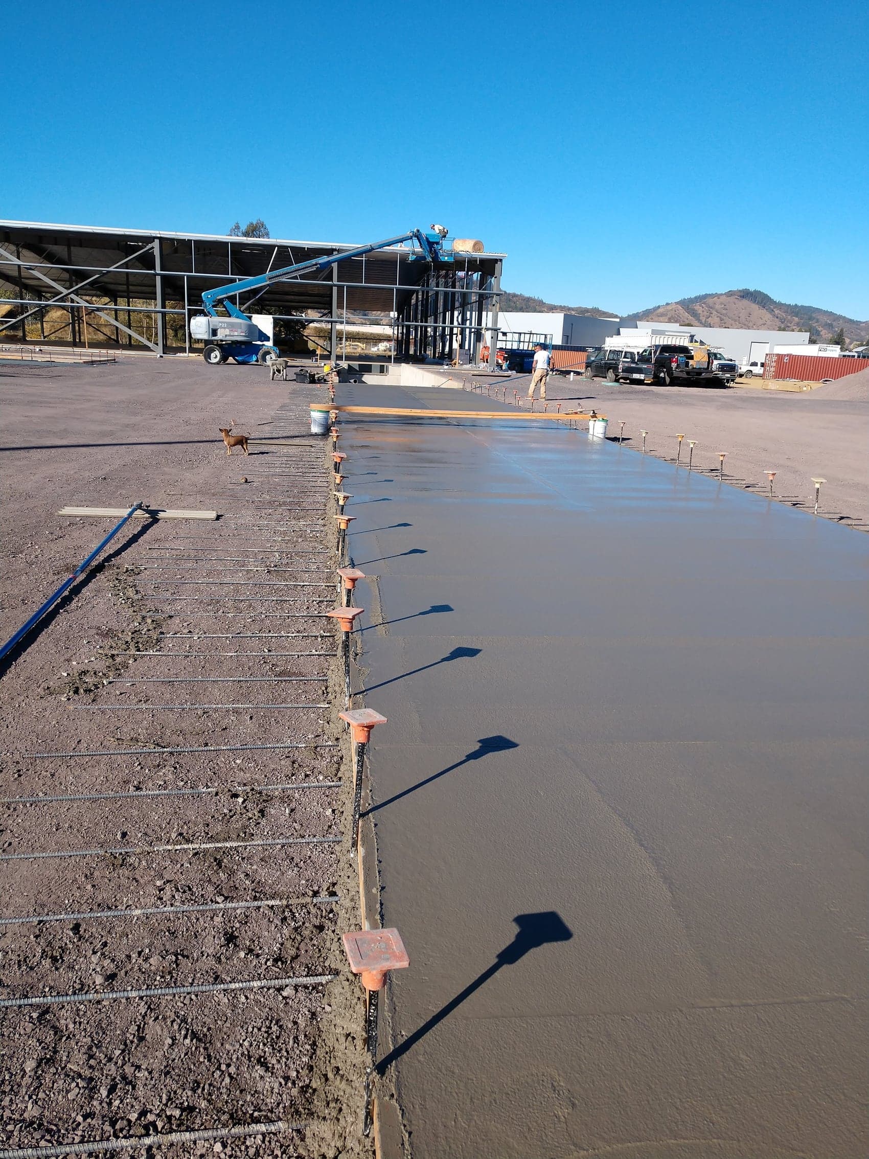 Fresh concrete being placed across the commercial pad from a pump line