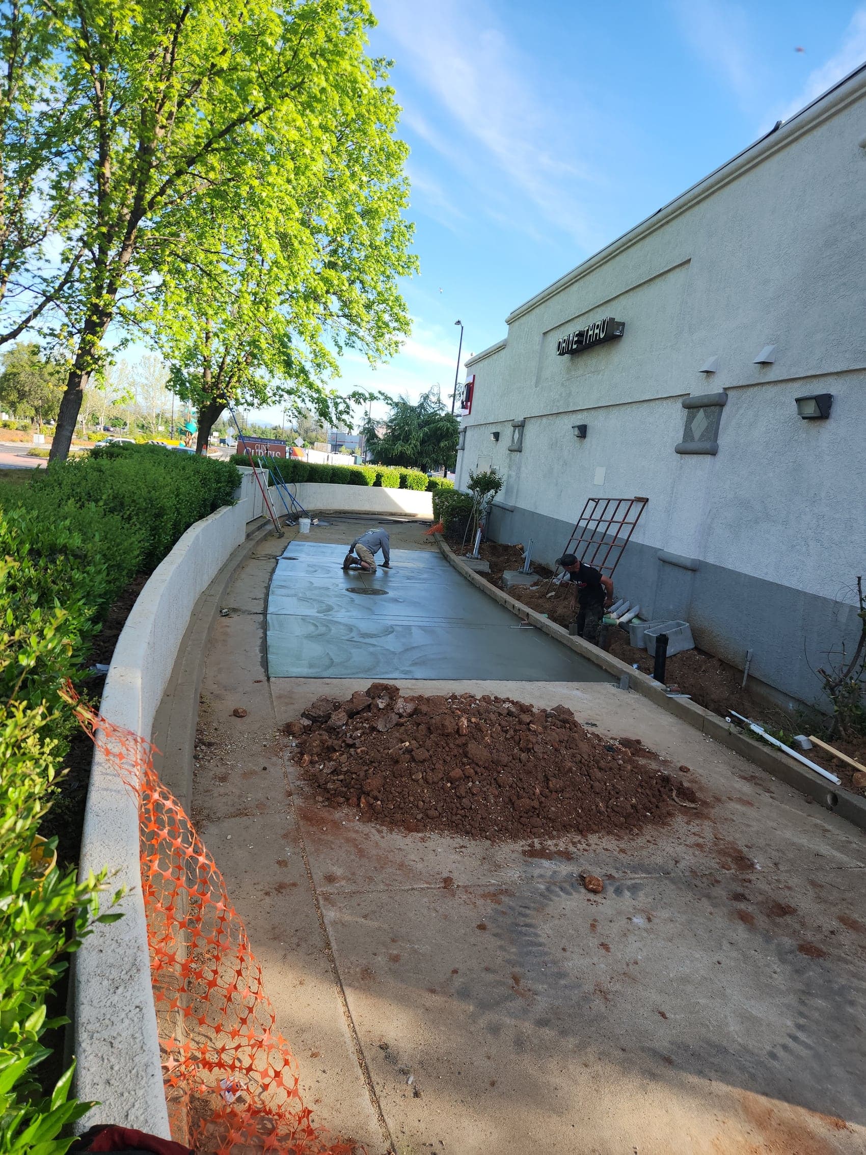 A drive-thru lane being replaced at a working business, freshly poured and fenced off from customers