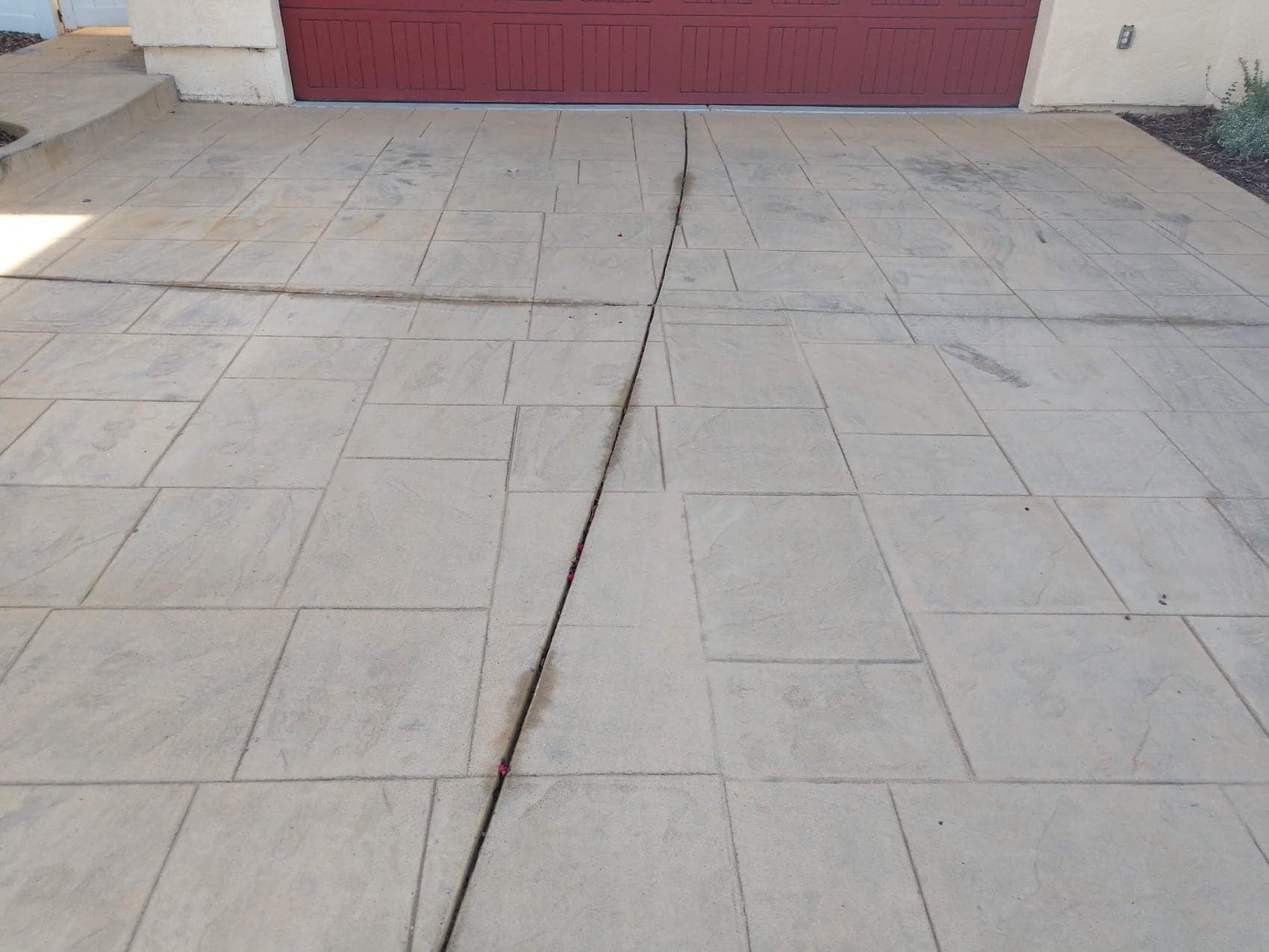 A large-format ashlar stamped driveway in a buff tone, running up to a garage
