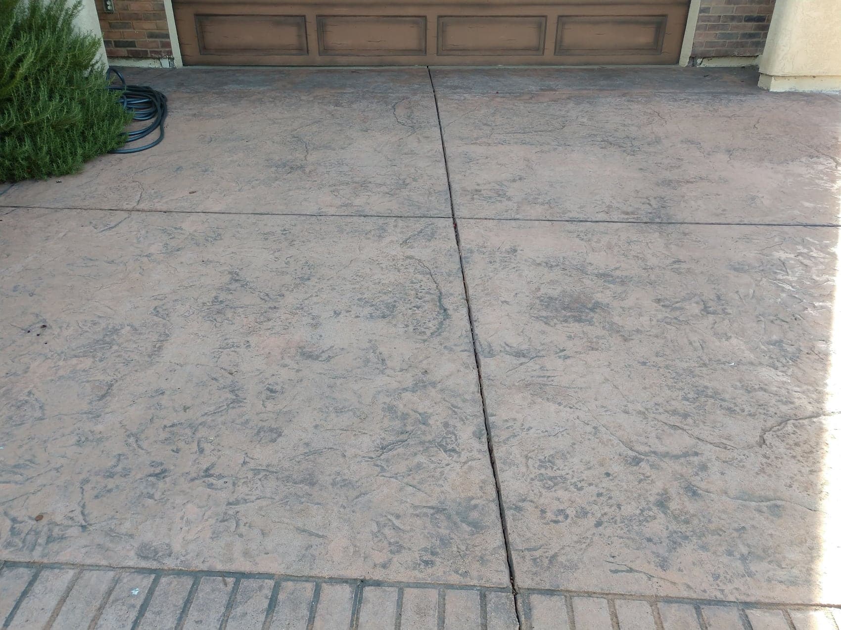 A seamless textured driveway in a warm tone with a contrasting brick border
