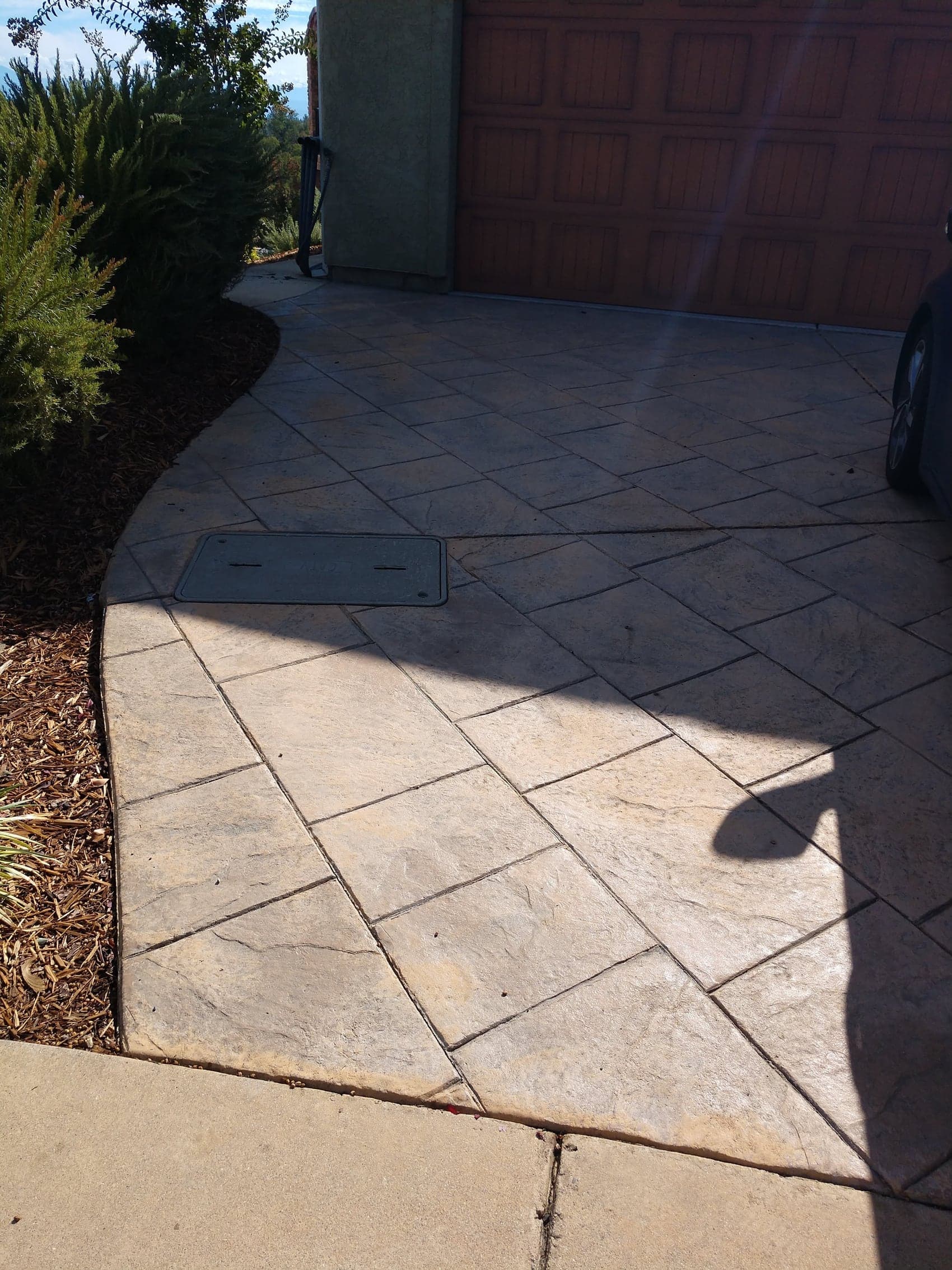 A stamped driveway with a curved edge sweeping around a planting bed