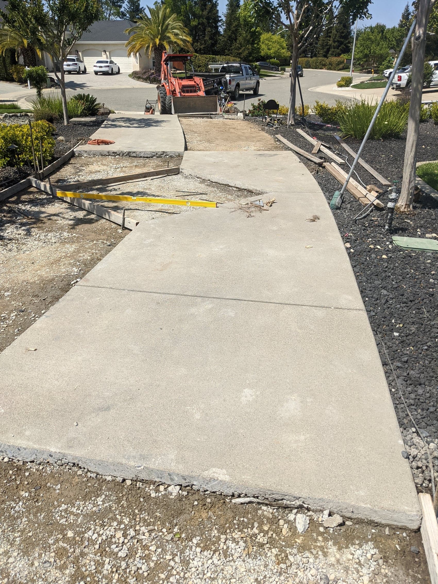 A finished walkway curving along a landscaped front yard